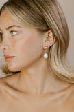 Close-up of a woman wearing pearl earrings with a neutral background