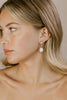 Close-up of a woman wearing pearl earrings with a neutral background